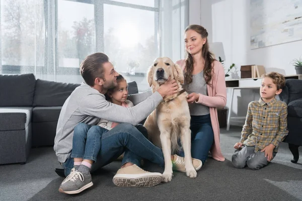 Семья сидит на полу с собакой — стоковое фото