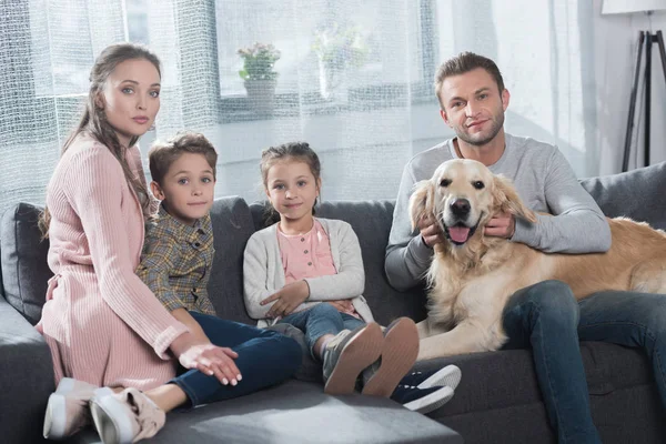 Family petting dog on couch — Stock Photo, Image