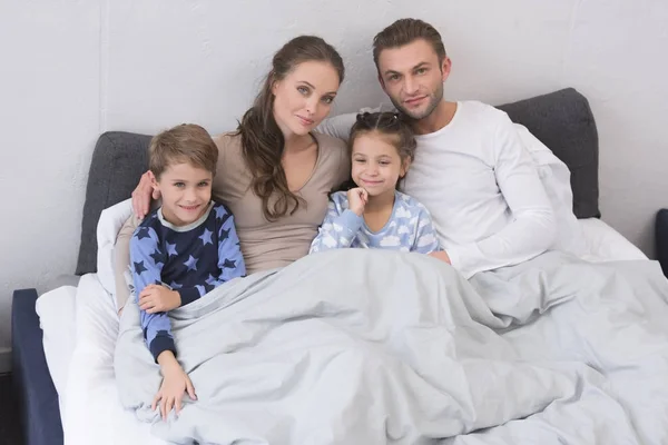 Familia acostada en la cama — Foto de Stock