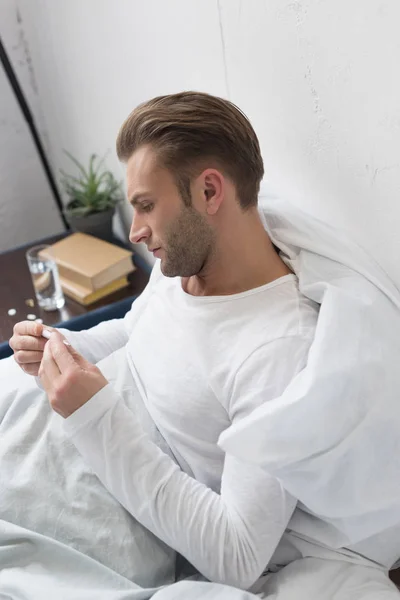 Sick man looking at thermometer — Stock Photo, Image