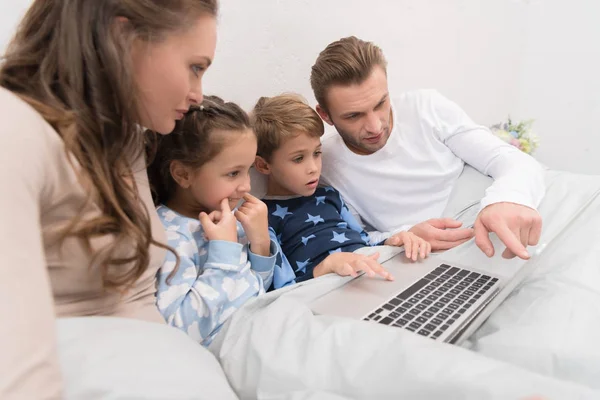 Familia acostada en la cama con portátil — Foto de Stock