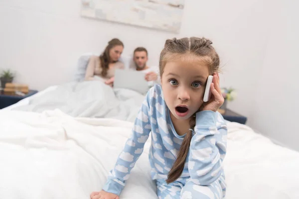 Meisje praten over smartphone op bed — Stockfoto