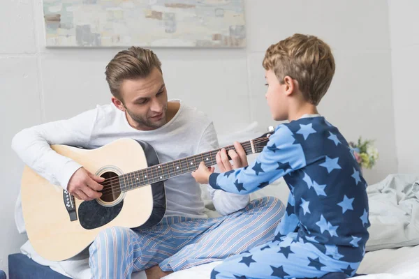 Padre mostrando hijo cómo tocar la guitarra — Foto de Stock