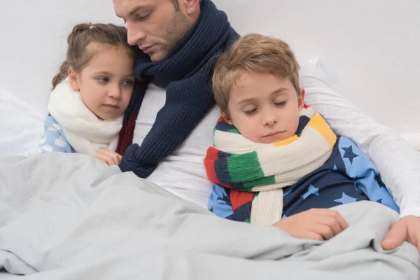 生病的父亲与儿子和女儿在床上 — 图库照片