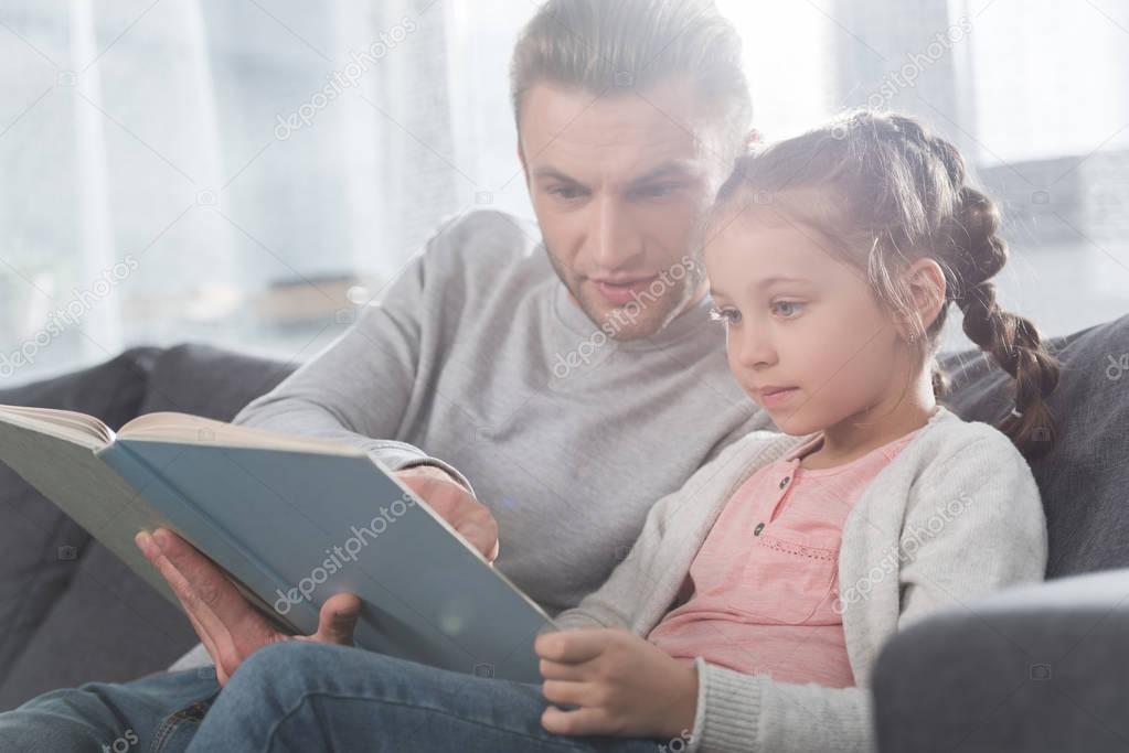 Father teaching daughter read at home