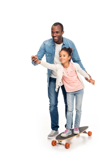 Отец учит дочь кататься на скейтборде — стоковое фото