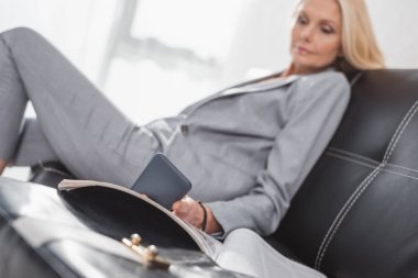 businesswoman using smartphone on couch clipart