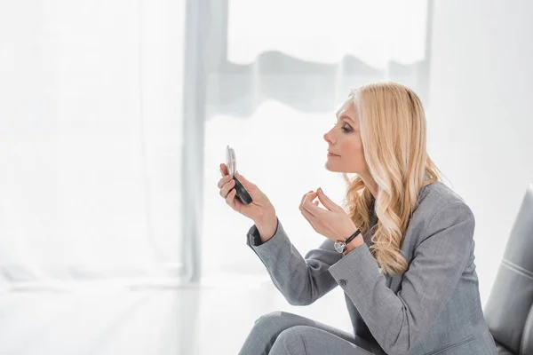 Businesswoman looking at cosmetic mirror — Stock Photo, Image