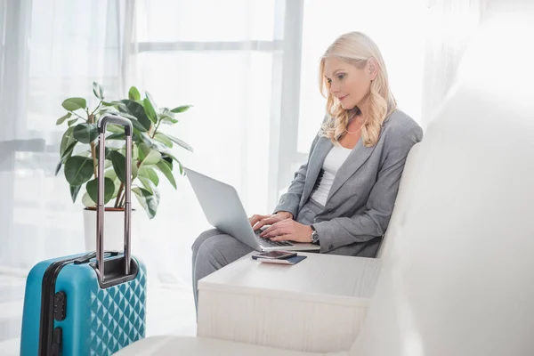 Businesswoman with luggage using laptop — Stock Photo, Image