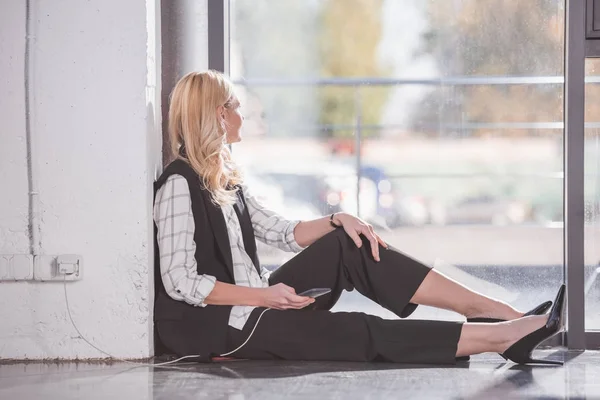 Mujer de negocios sentada en el suelo y cargando teléfono — Foto de Stock