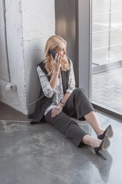 Businesswoman charging smartphone and making call — Stock Photo, Image