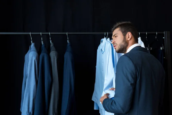 Бизнесмен выбирает костюм в бутике — стоковое фото