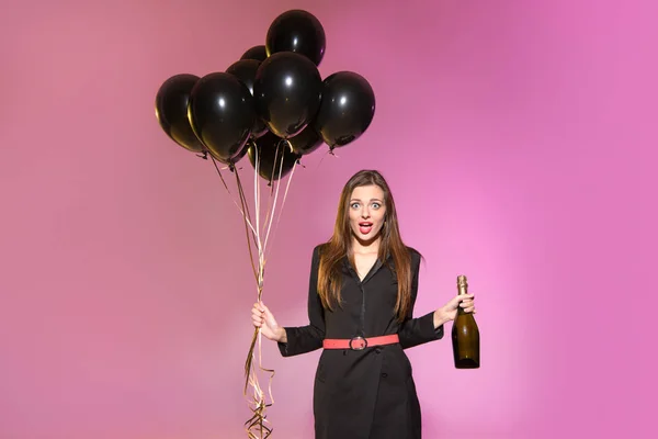 Mulher com garrafa de champanhe e balões pretos — Fotografia de Stock