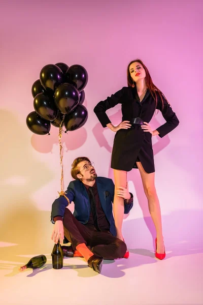 Couple with champagne bottles and black balloons — Stock Photo, Image