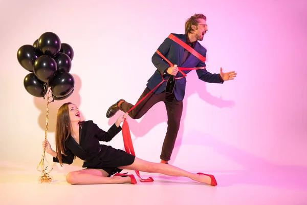 Girl holding man bound with ribbon — Stock Photo, Image