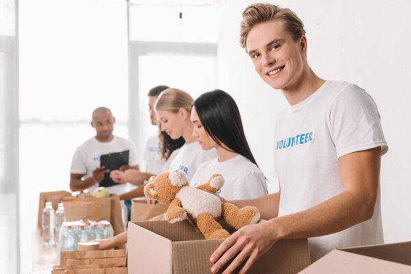 волонтер с плюшевым мишкой и коробкой

