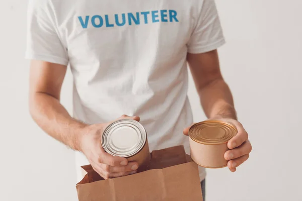 Voluntário colocando latas de lata em saco de papel — Fotografia de Stock