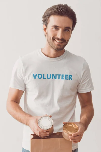 Volunteer putting tin cans in paper bag — Stock Photo, Image