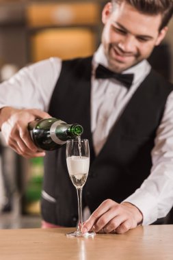 Barmen bardağa şampanya dolduruyor.