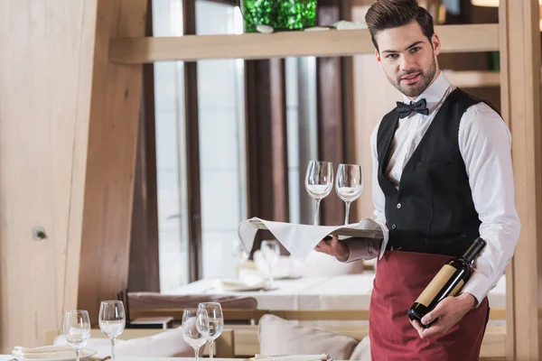 Waiter holding wineglasses and bottle — Stock Photo, Image