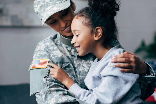Datter som klemmer mor i militæruniform – stockfoto