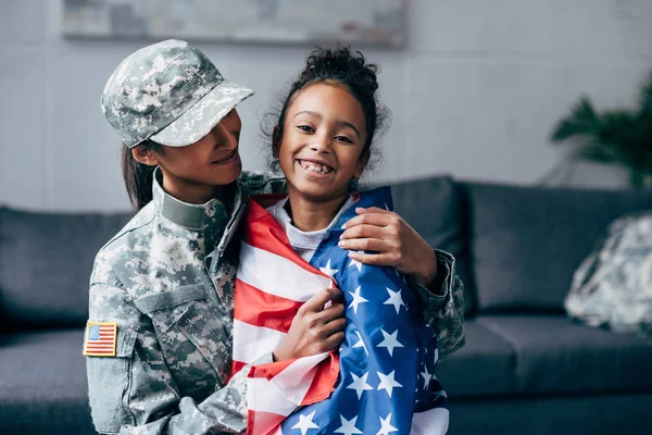 Soldado e filha envolvidos com bandeira americana — Fotografia de Stock