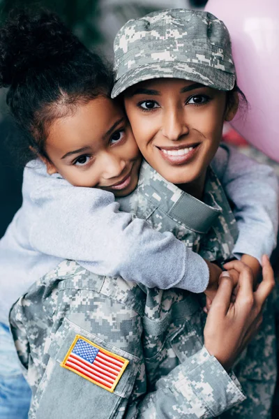 Hija abrazando madre en uniforme militar — Foto de Stock