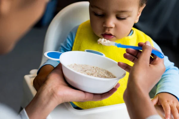 Pequeno filho comer mingau — Fotografia de Stock
