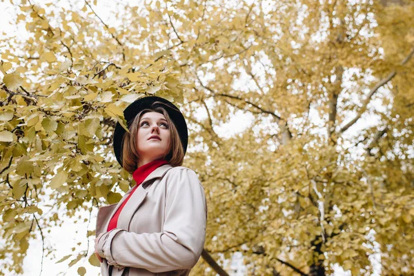 Vrouw in trenchcoat en hoed in park — Stockfoto