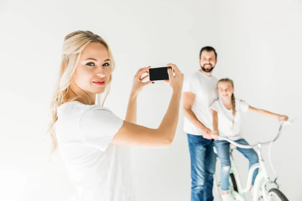Женщина фотографирует семью со смартфоном — стоковое фото