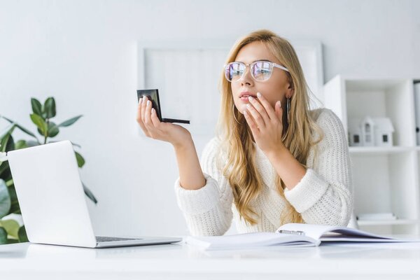 business woman doing makeup at workplace
