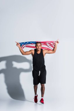 Amerikan bayrağı tutarak ve gri çalışan genç Afro-Amerikan sporcu