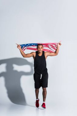 young african american sportsman holding american flag and running on grey clipart