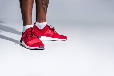 gri izole Afro-Amerikan erkek spor ayakkabı ayakta kısmi görmek