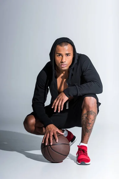 Sportlicher Afrikanisch Amerikanischer Mann Hockt Mit Basketballball Und Blickt Die — Stockfoto