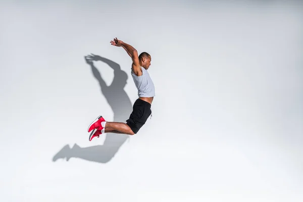 Vista Lateral Del Joven Deportista Afroamericano Saltando Sobre Gris —  Fotos de Stock