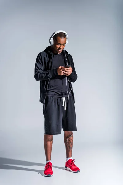 Lächelnder Junger Afrikanisch Amerikanischer Sportler Mit Smartphone Auf Grau — Stockfoto