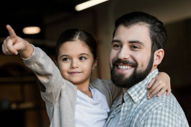 neşeli kızı babası sarılma ve evde bir şeye işaret