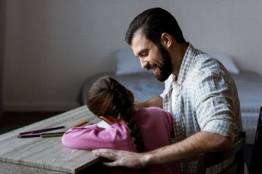 Baba küçük kızı masada oturan ve evde defterine çizim ile yan görünüm