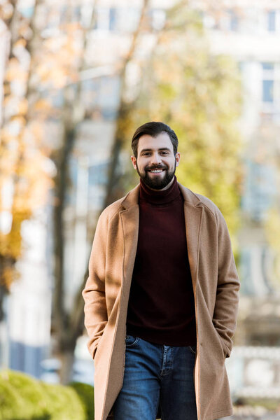 smiling handsome man in autumn outfit looking at camera. outside