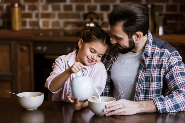 父と娘のキッチンで軽食をボウルにミルクを注ぐ — ストック写真