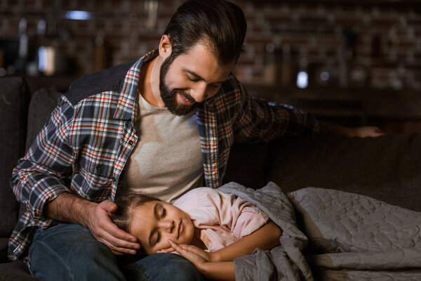 little daughter fall asleep on fathers knees at home