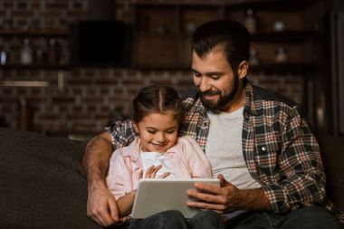 mutlu baba ile kızı kanepede oturan ve tablet kullanma