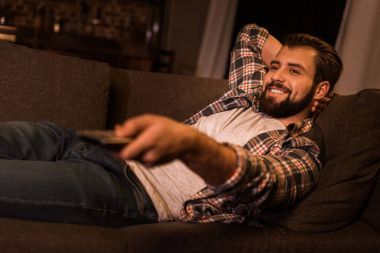 kanepede döşenmesi ve evde tv izlerken bir genç adam