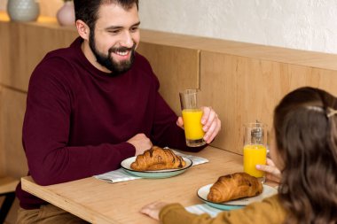 Baba ve kızı kafede portakal suyu içme
