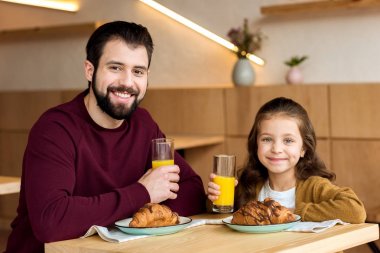Baba ve gözlük suyu ile tutarak ve kameraya bakarak kız gülümseyerek