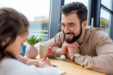 gülümseyen baba kızı o renkli kalemle çizim sırasında bakarak