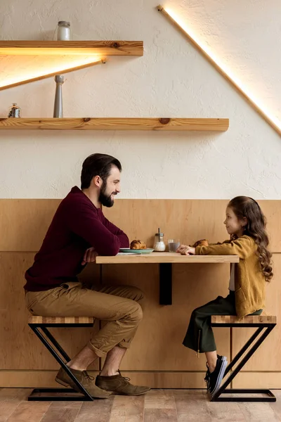父亲和女儿坐在咖啡馆与牛角面包 — 图库照片