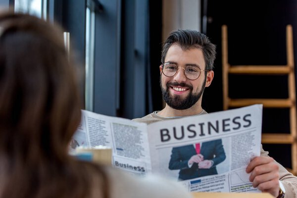 smiling father reading business newspaper while spending time with daughter in cafe  