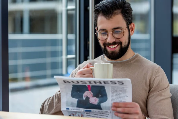 Lächelnder Mann Trinkt Kaffee Mit Marshmallow Und Liest Wirtschaftszeitung — Stockfoto
